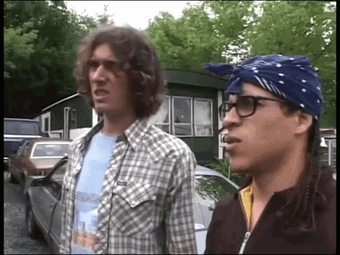 a man wearing glasses and a bandana is smoking a cigarette