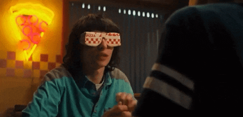 a man wearing a pair of sunglasses that say pizza is sitting at a table .
