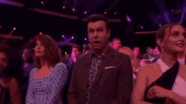 a man in a suit and tie is standing in front of a crowd of people .