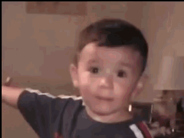 a young boy in a black shirt is standing in a room with his arms outstretched