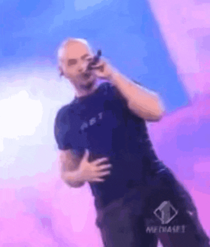 a man singing into a microphone with a shirt that says art