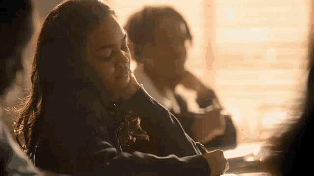 a woman is sitting at a desk in a classroom with her eyes closed .