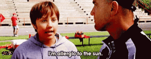 a man and a boy are talking on a field and the boy says " i 'm allergic to the sun "