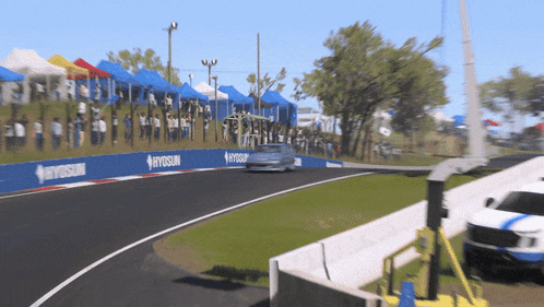 a car driving down a race track with a hyosun banner on the side