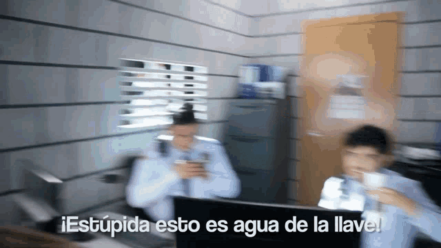 a blurry picture of a man sitting in front of a computer with the words " estupida esto es agua de la llave "