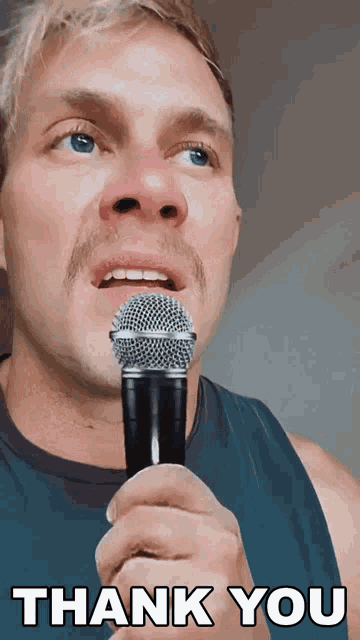 a man with a red nose holds a shure microphone in front of his face and says thank you