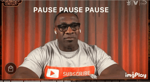 a man wearing a t-shirt that says subscribe is sitting in front of a red curtain