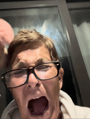 a man with glasses is making a funny face with his mouth open