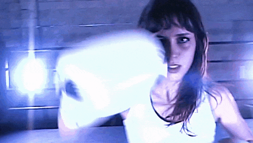 a woman wearing white boxing gloves throws a punch in the air