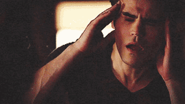 a man in a black shirt is holding his head