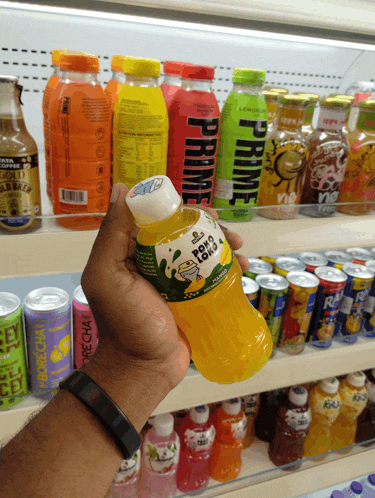 a person is holding up a bottle of orange juice with the word prime on the front