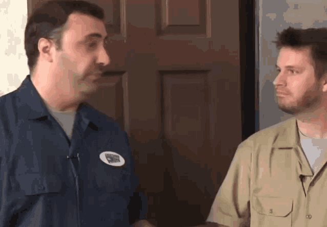 two men are standing next to each other in front of a door and one has a patch on his shirt that says emergency service