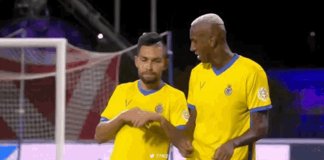 two soccer players are standing next to each other on the field .