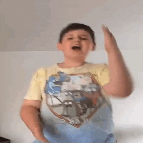 a young boy wearing a yellow t-shirt with a picture of cars on it