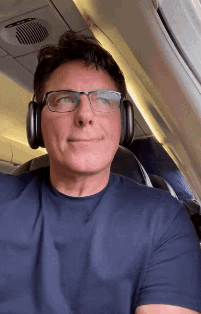 a man wearing glasses and headphones is sitting on a plane