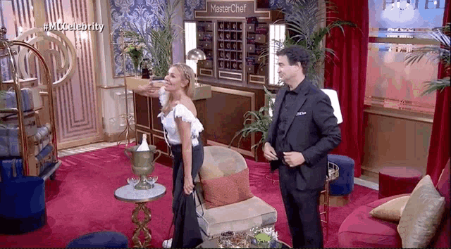 a man and woman are standing in a room with a sign that says masterchef on it