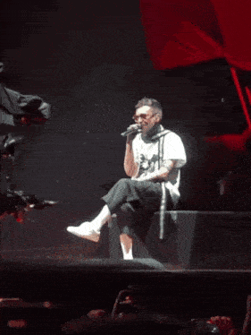 a man in a white shirt is singing into a microphone on a stage in front of a crowd