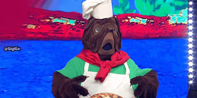 a pug wearing a chef 's hat and apron holding a pizza