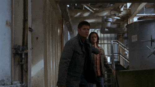 two men are walking down a hallway with a sign on the wall that says ' a ' on it