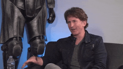 a man sits in front of a statue with a bottle of aquafina water nearby