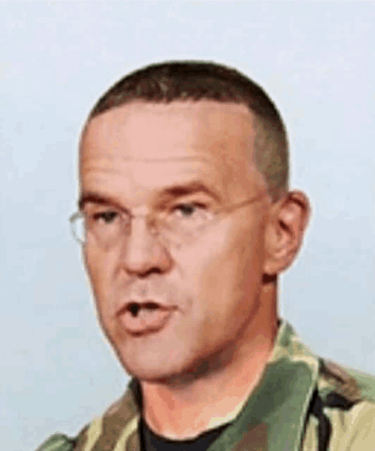 a close up of a man wearing glasses and a camouflage uniform .