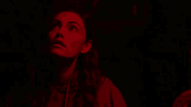 a woman in a red light looks up