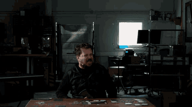 a man with a mustache is standing in front of a table with a stack of cards on it