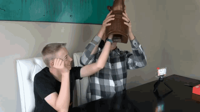 a man in a plaid shirt is holding a brown object over his face