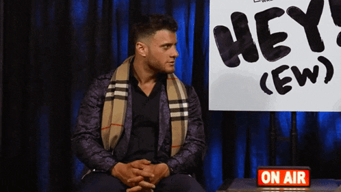 a man is sitting in front of a sign that says hey crew
