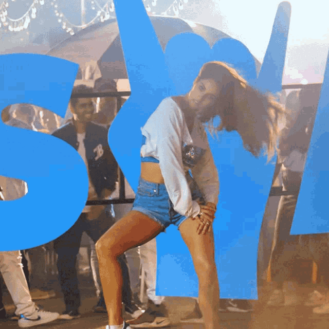a woman is dancing in front of a large blue letter s.