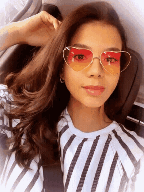 a woman wearing heart shaped sunglasses is taking a selfie