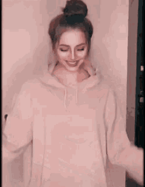 a woman in a hoodie is sticking her tongue out while standing in front of a door .