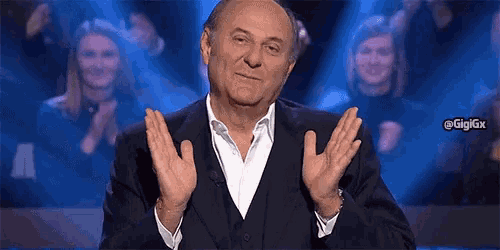 a man in a suit is clapping his hands in a crowd