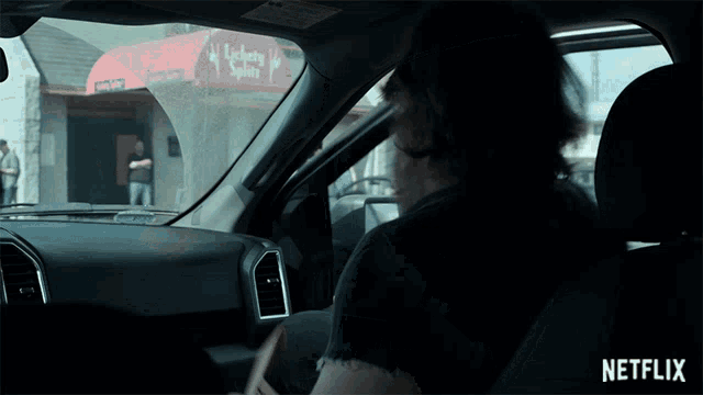 a man driving a car with a netflix logo on the bottom