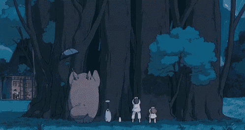 a group of people are standing next to a tree in the woods .