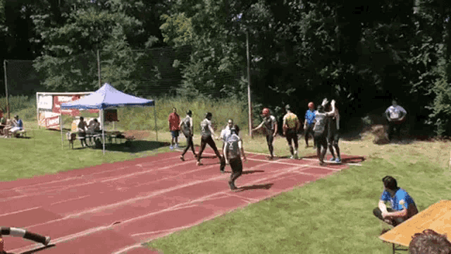 a group of people are running on a track and one of them is wearing a blue shirt with the word lotto on it