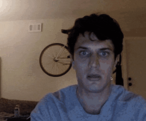 a man is making a funny face in front of a bicycle hanging on the wall