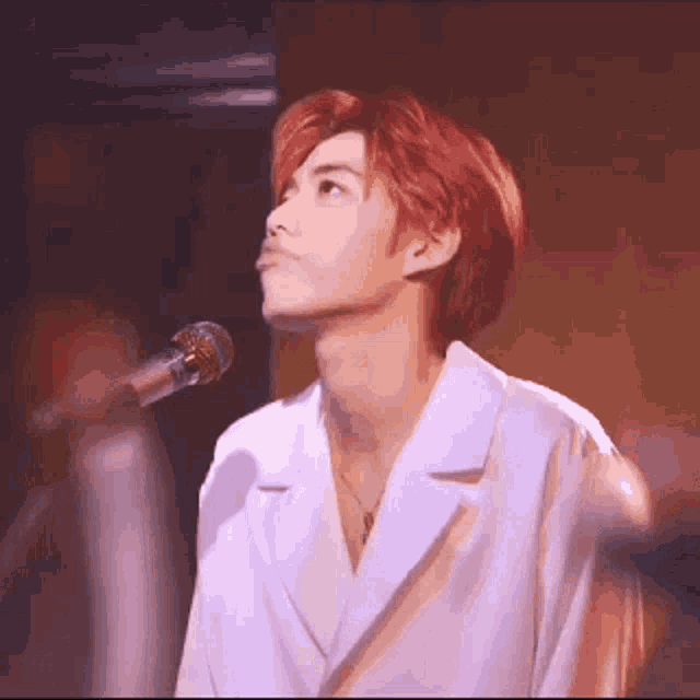 a young man with red hair is standing in front of a microphone .
