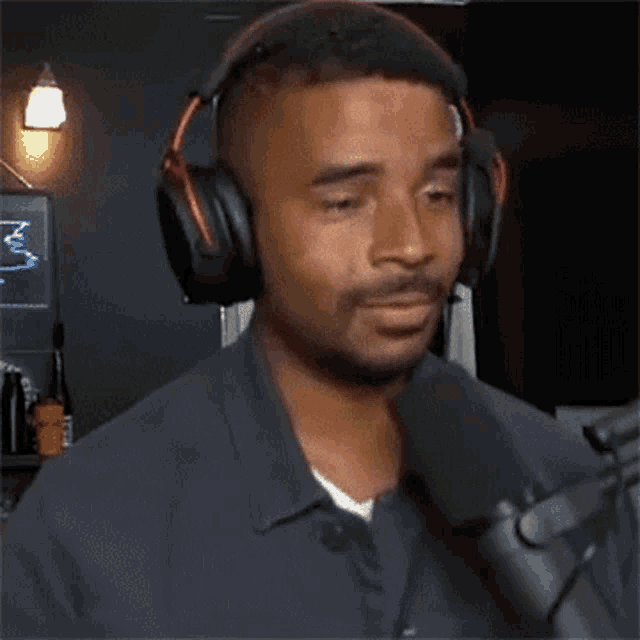a man wearing headphones is talking into a microphone with his eyes closed