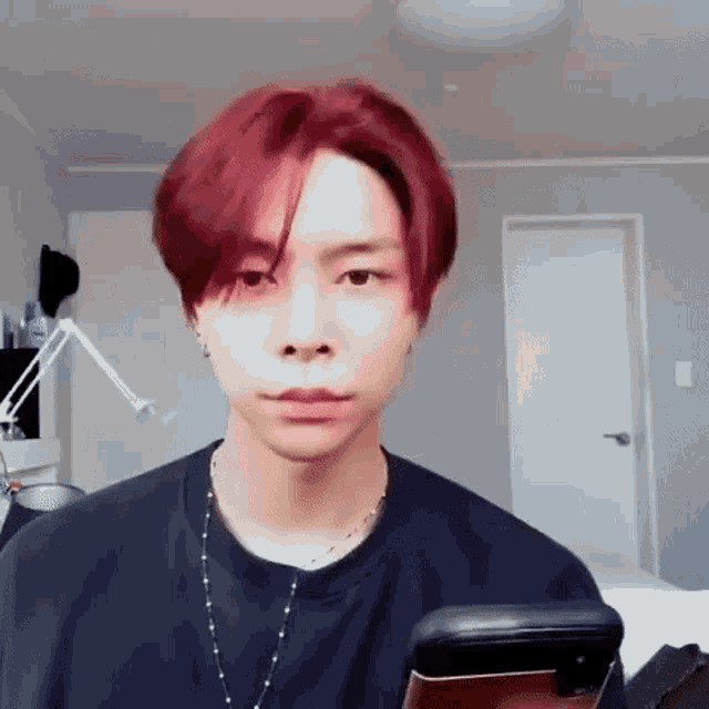 a man with red hair is holding a cell phone in his hand .