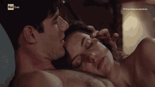 a man and a woman laying on a bed with rai 1 hd on the bottom right