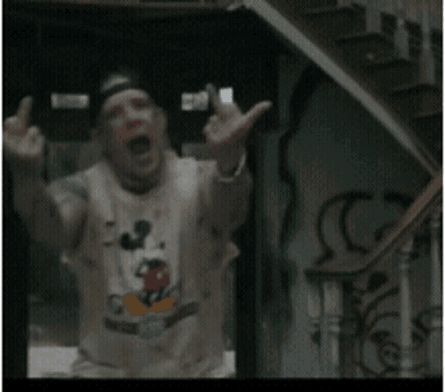 a man wearing a mickey mouse shirt is making a funny face