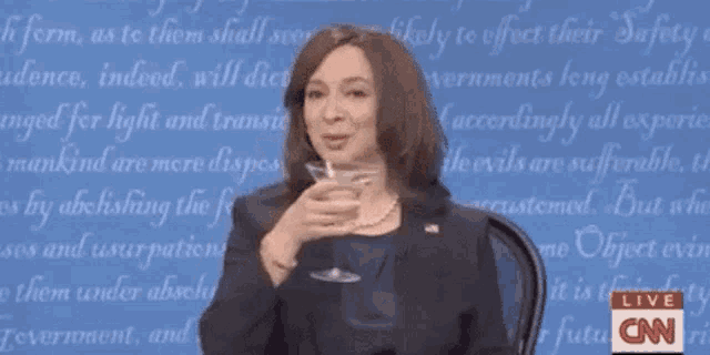 a woman is holding a glass of wine in front of a cnn logo