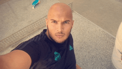 a bald man taking a selfie wearing an adidas shirt