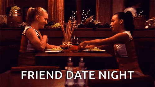 two cheerleaders are sitting at a table with plates of food and the words friend date night above them .