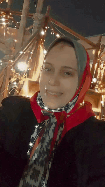 a woman wearing a red scarf and a black jacket smiles