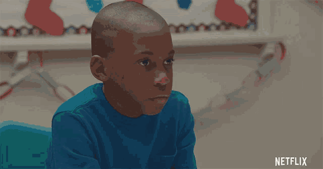 a boy in a blue shirt sits in front of a netflix sign