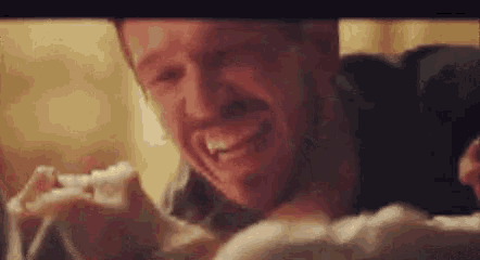 a close up of a man laughing while holding a baby .