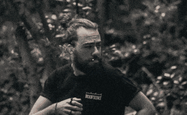 a man with a beard wearing a black shirt that says broken silence