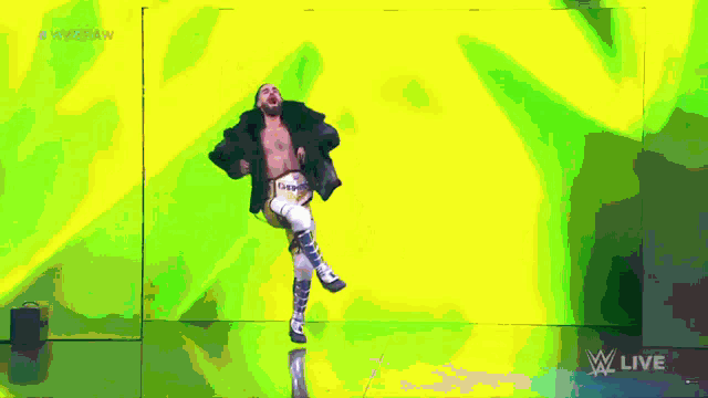 a man is dancing in front of a screen that says ' wwe live ' on it